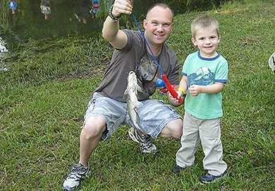 Smiling Father and Son showing a catfish caught at a DNR Fishing Rodeo