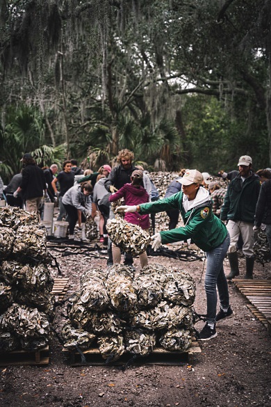 Ryan Raiford, quien trabaja con SCORE, lanza una bolsa de conchas reciclados al montón que será plantado en las costas de Carolina del Sur en unos meses. (Foto por Dylan Schmitz)