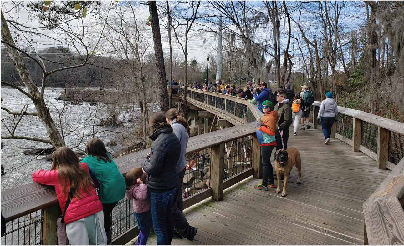 Winding view of Saluda riverwalk boardwalk with many visitors enjoying the view