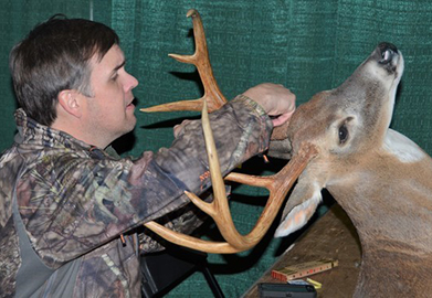 Camo-dressed person measuring antlers