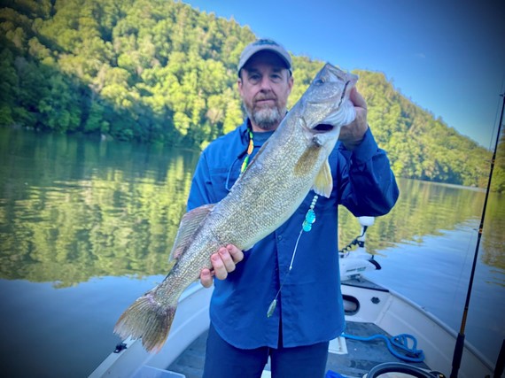 man holding walleye on a boat