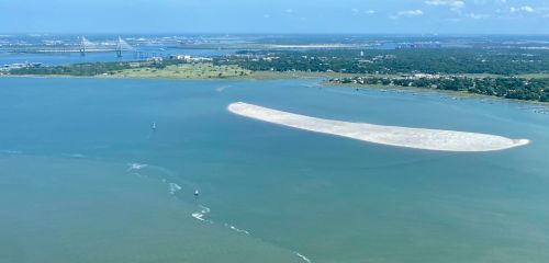 an overview shot of the crab bank sitting in the water with land in the background