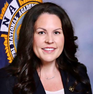 Lt. Charlotte M. McKee in front of an FBI academy flag.