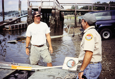 Old photo of two men in SCDNR uniforms smiling at each other