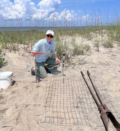 a woman standing in the sand with some tools