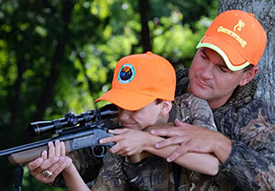 Mentor showing boy how to hold a rifle