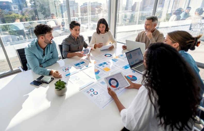 A group discusses graphs around an office table