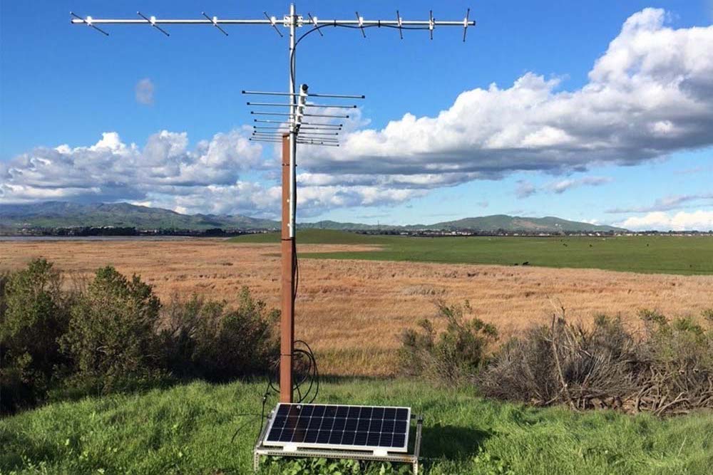 A solar panel and MOTUS tower overlooking a valley and mountains